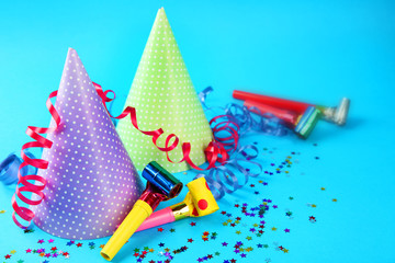 Two Birthday hats with serpentine streamer and noise makers on blue background