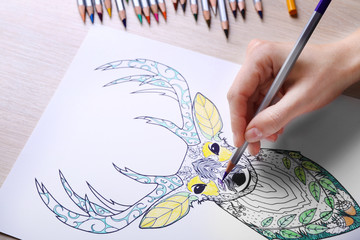 Obraz premium Female hand drawing with crayon in adult anti stress coloring closeup