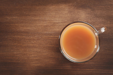 Tea with milk on wooden background.