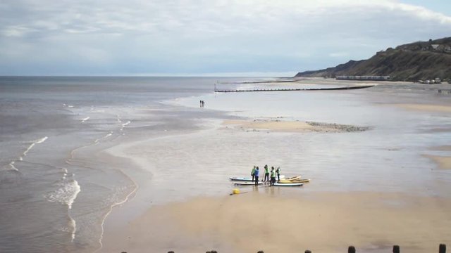 A group of unidentifiable people having a surfing debriefing on a beach in the UK 