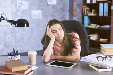 Young woman with tablet falling asleep at the table