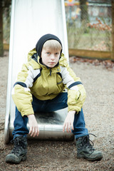 Single lonely child sitting on slide