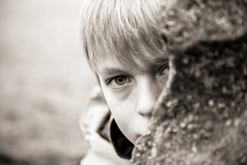 Close up of child peeking from behind rock