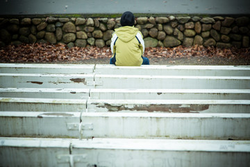 Back of lonely child sitting on bench