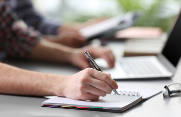 Student's hand writing in exercise book at the table