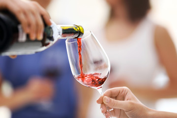 Pouring red wine from bottle into glass, close up