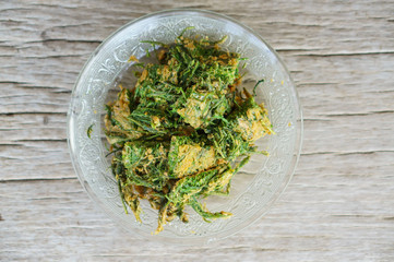 Cha-om omelet in white plate on wood background