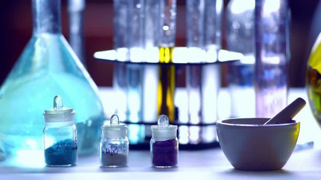 Flasks with yellow and blue reagents, test tubes and beakers in a chemical laboratory,  blurred background, filmed on telephoto lens