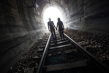 Couple walking together through a railway tunnel