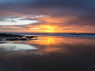 Fototapeta na wymiar Sunset at the beach with intense glowing orange, yellow, red col
