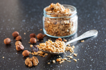muesli in a spoon from a jar on a table, selective focus