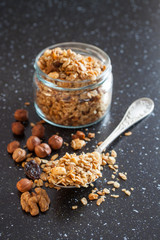 muesli in a spoon from a jar on a table, selective focus