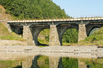 Fototapeta na wymiar The bridge from a stone on the railroad