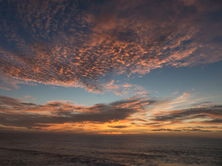Fototapeta na wymiar Sunset over the Atlantic Ocean composing a dramatic orange cloud