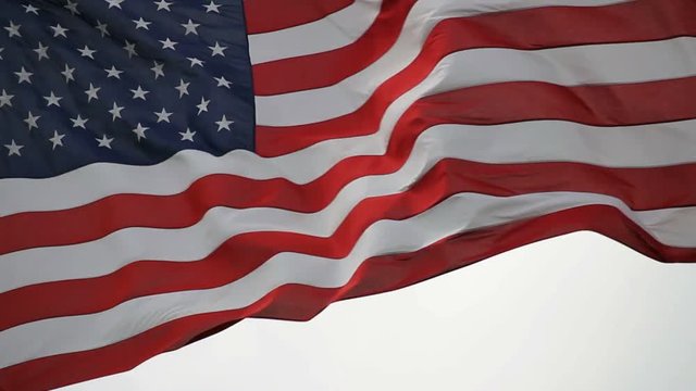 Stars and Stripes flag of the United States of America flying high on a windy day close up 1080p