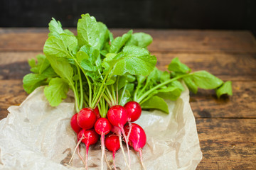 garden radish with a tops of vegetable on a table, selective focus