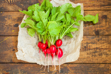 garden radish with a tops of vegetable on a table, selective focus