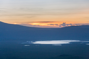 Panoramic view of huge Ngorongoro caldera (extinct volcano crater) with lake against evening glow background at dusk. Great Rift Valley, Tanzania, East Africa.
