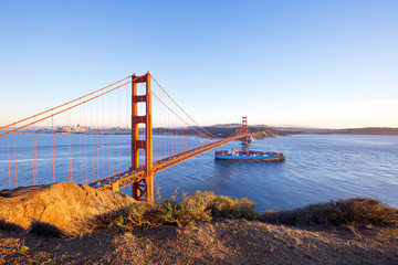 gold gate bridge and container ship on sea in sunny day