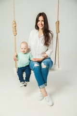 Young woman with little son sitting on swing