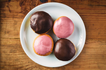 Donuts with sweet topping on a plate, top view
