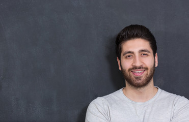 Obraz premium Handsome Young Man Smiling at the Camera Against chalkboard Wall
