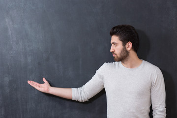 Handsome man with beard showing something on chalkboard, copy sp