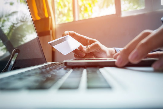 Man holding credit card in hand and entering security code using