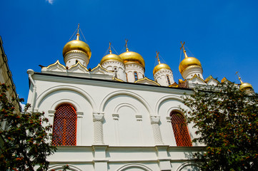Золотые купола и кресты Собора пресвятой богородицы на территории Московского Кремля на фоне голубого неба. 
Golden domes and crosses of the Cathedral of the Blessed Virgin in the Moscow Kremlin 