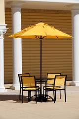 Outdoor table with yellow umbrella and chairs