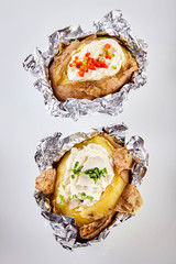 Two barbecued baked potatoes in tin foil