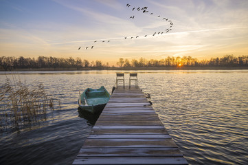 Łódka zacumowana przy drewnianym pomoście w piękny poranek nad jeziorem