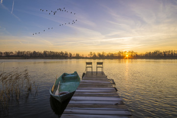 Łódka zacumowana przy drewnianym pomoście w piękny poranek nad jeziorem