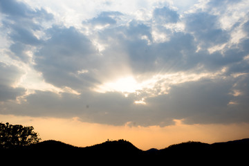 Sunlight in cloudy sky with silhouette mountain