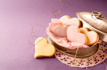 Colorful fondant heart shaped biscuits in a tin