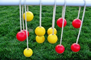 Yellow and red balls hanging on the rops against green grass