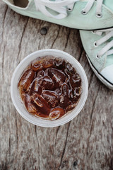 Cola with ice cubes and sneakers