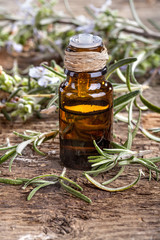Essential oil made from rosemary on rustic table