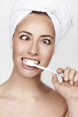 Young woman pulling face and brushing teeth