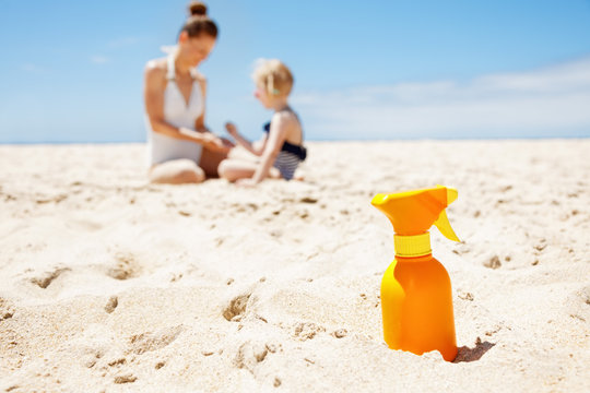Closeup On Sunscreen Bottle On Beach. Family In Background