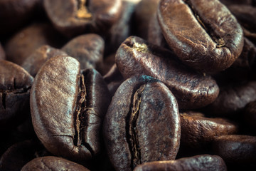 Macro closeup photo of roasted coffee beans laying on the wooden table. Natural coffee beans. Black coffee seeds. Brown aroma composition of coffee beans flavor.
