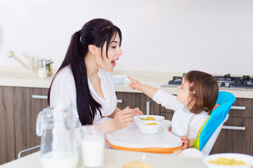 Mum spoon feeding child in kithen