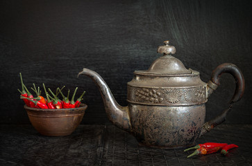 Food background with antique iron kettle and hot chili pepper.