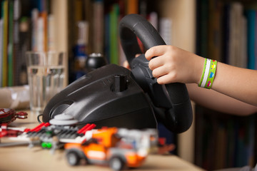 Close up of child's hands holding a computer steering wheel. Future driver. Getting ready for professional driving. Kid's hands driving a car.