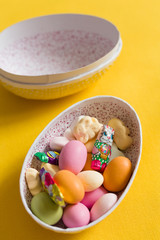 Easter egg box with candy and chocolate, scandinavian tradition. close up on yellow backgorund.  big Easter egg full of sweets and cookies. celebrating Easter. easter surprise.