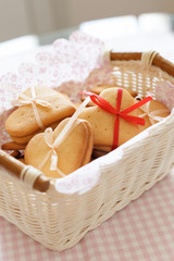 White basket with homemade crispy cookies decorated with thin ribbons. Cookies on the table. Preparations for holiday season. Baking at home.