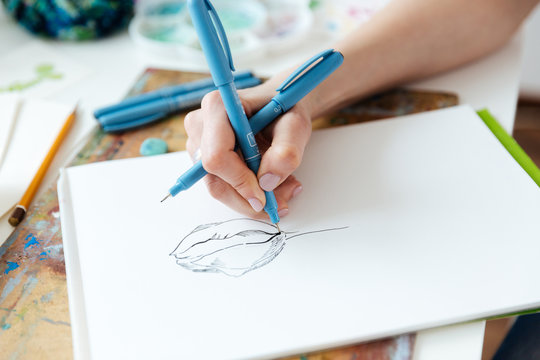 Woman artist hands drawing with gel ink pen in sketchbook