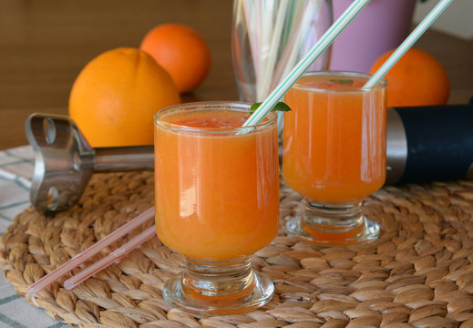 Two glasses of fresh grapefruit,orange and papaya smoothie on a wooden table. 
