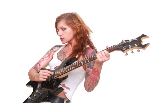Attractive redhead punk girl with tattoos playing electrical guitar