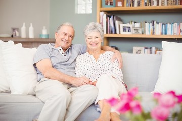 Portrait of smiling senior couple sitting on sofa in living room